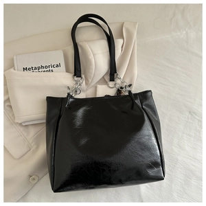 Close-up of black oil wax leather tote bag with silver chain straps and glossy texture