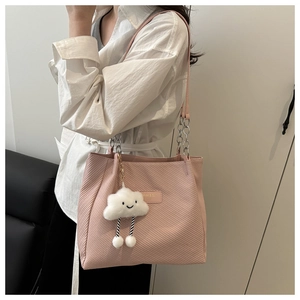 Détail du sac cabas rose avec texture sergée, bandoulière chaîne et breloque nuage blanc