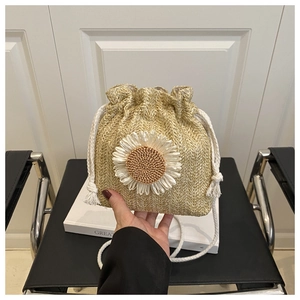 Detail of straw woven bucket bag featuring 3D daisy flower and white drawstring handle