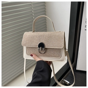 Detail of woven texture and metallic clasp on contrast minimalist crossbody bag
