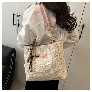 Dettaglio della borsa tote in paglia con tracolla in pelle rosa e fiocco floreale