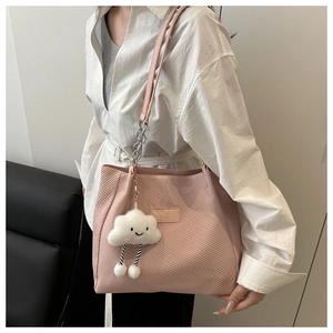 Detail of pink corduroy tote bag with soft ribbed texture and plush cloud charm