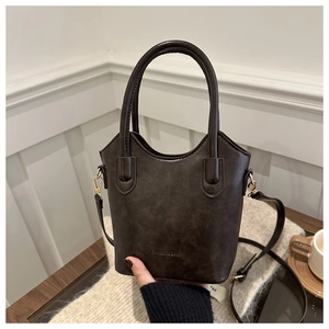 Detail of dark brown leather bucket bag with gold hardware and embossed fashion logo