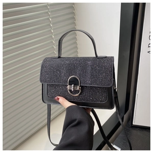 Detail of black glitter crossbody bag with silver oval metal lock and glossy finish