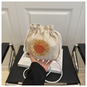 Detail of hand-woven beige herringbone bucket bag featuring a large sunflower accent