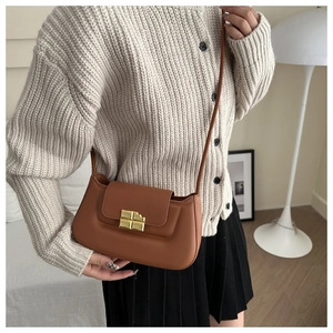 Detail of caramel brown leather saddle bag with unique gold chocolate bar shaped buckle