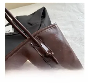Close-up of vintage brown leather tote bag texture with elegant gold metal logo plate