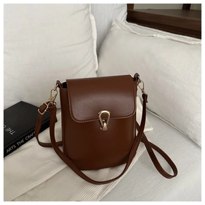 Détail d'un sac bandoulière en cuir marron foncé avec fermoir métallique doré en goutte d'eau