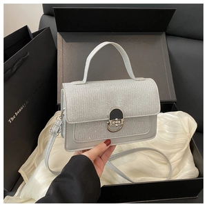 Detail of silver glitter small square bag with metal lock handle and adjustable strap