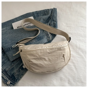 Flachbild einer beigen Nylon-Halbmondtasche mit verstellbarem Riemen auf weißem Stoff