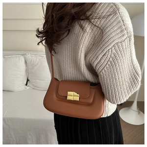 Detail of caramel matte leather shoulder bag with a gold chocolate-shaped metal buckle