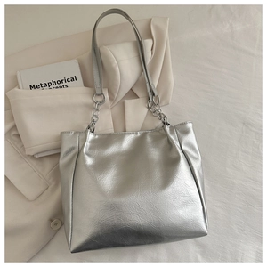 Silver metallic tote bag detail with lychee texture and metal chain handles on a suit