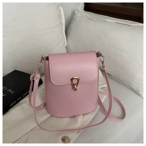 Détail d'un sac seau rose avec fermoir doré unique et crochets de bandoulière en métal