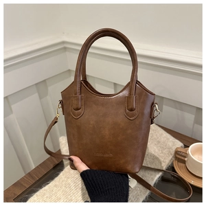 Detailed view of a vintage brown leather tote bag with embossed fashion text and gold hardware