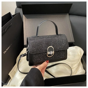 Close-up of black sequined flap bag with metal lock inside premium gift box