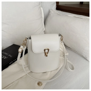 Détail du sac seau blanc avec boucle fer à cheval dorée sur fond texturé doux