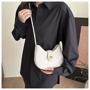 Détail d'un sac demi-lune blanc avec fermoir métallique doré porté par un mannequin