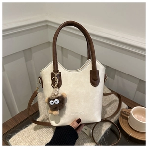 Chic cream bucket bag detail with brown plush monster charm and adjustable strap