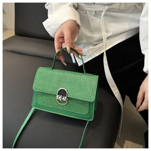 Detail of green woven crossbody bag with metallic silver twist lock and sequin texture