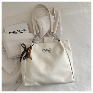 Detail of cream PU leather tote bag with silver bow charm and elegant ribbon handle