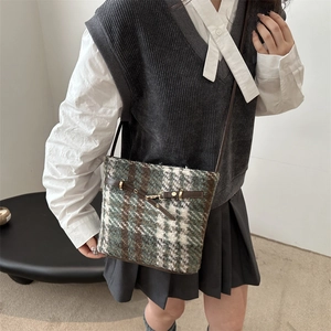 Close-up of vintage green plaid tweed crossbody bag with brown leather trim and gold buckle