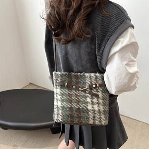 Detail of tweed checkered crossbody bucket bag with brown leather trim and gold hardware