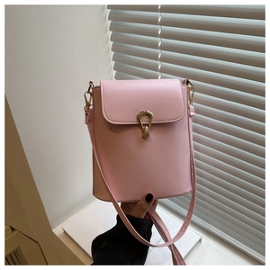 Close-up of pink leather bucket bag featuring a decorative gold geometric lock and strap