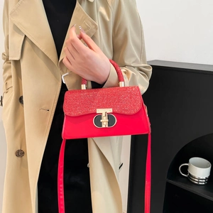 Elegant red square handbag with gold metal clasp and textured flap shown in hand