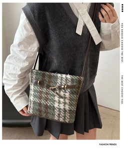 Detail of green and brown plaid tweed bucket bag with vintage metal buckle for women