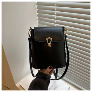 Close-up of sleek black bucket bag featuring an elegant U-shaped golden metallic twist lock