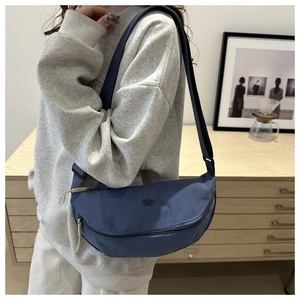 Detail der blauen Halbmond-Satteltasche mit Metall-Logo und Web-Schultergurt