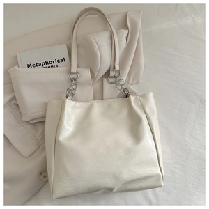 Close-up of cream tote bag featuring silver chain straps and soft leather texture