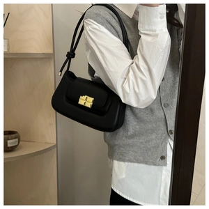 Close-up of a black leather underarm bag with gold hardware buckle and slim strap