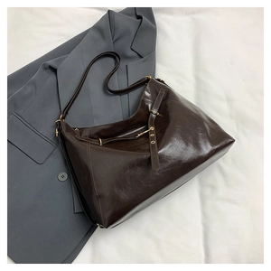 Detailed view of the dark brown oil wax leather texture and golden buckle on tote bag