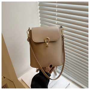 Detail of beige bucket bag with gold lock closure and adjustable leather shoulder strap