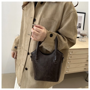 Detail of dark brown vintage bucket bag with embossed logo and matte faux leather texture
