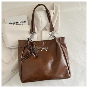 Detail of dark brown tote bag with oily leather texture and silver bow decoration