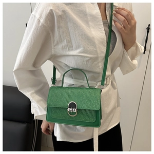 Sparkling green glitter mini flap bag with silver ring buckle shown worn by a model