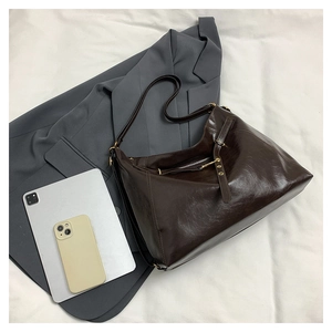 Detail of a large vintage brown tote bag made of glossy leather for office commute