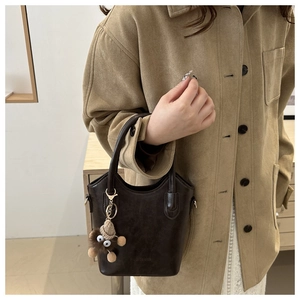 Detail of dark brown vintage bucket bag featuring a plush charm and fashion embossing