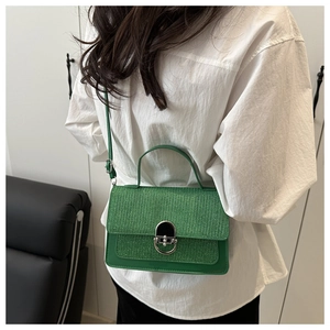 Close-up of green shoulder bag with glitter flap and silver buckle worn by a model
