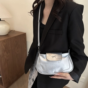 Silver retro square crossbody bag with metallic bow detail worn by model in lifestyle setting