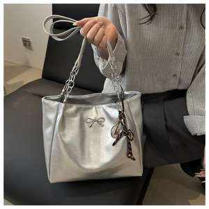 Detail of silver metallic tote bag featuring pleated texture and mini metal bow buckle