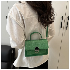 Detail of glittery grass green crossbody bag with metal twist lock and slim strap