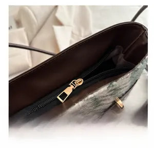 Detailed close-up of smooth gold metal zipper on a plaid texture crossbody bag