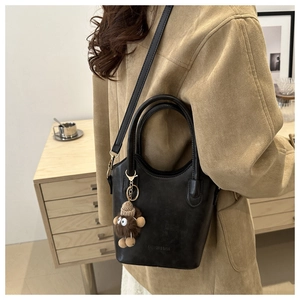 Detail view of retro black bucket bag with plush charm and fashion brand lettering