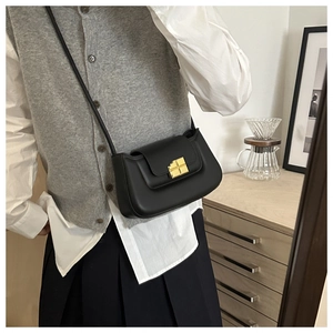 Detail view of the sleek black leather mini bag with its square golden metallic lock