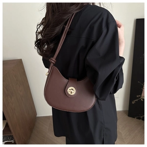 Detail of a brown shoulder bag with a gold metal lock and decorative knot on strap