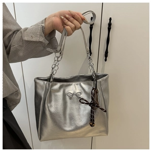 Detail of silver tote bag with metallic texture, bow hardware and chain strap handle