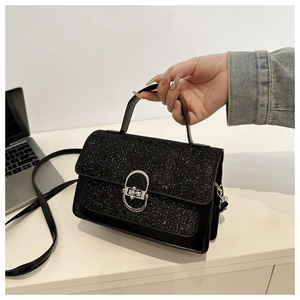Detail of black sequined flap handbag featuring a silver oval twist lock and sleek leather